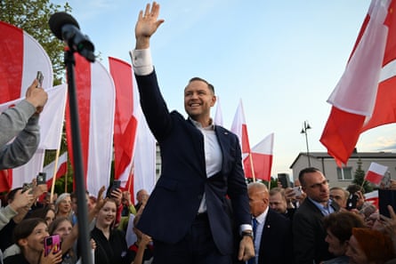 Karol Nawrocki waving amid flags