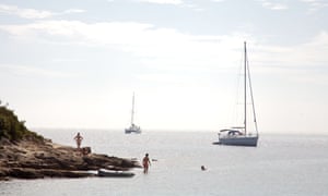 Boats moored off Sveti Klement Island and a couple of swimmers, Croatia.