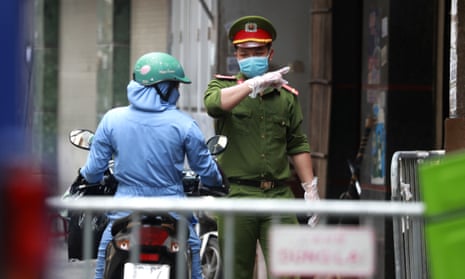 A police officer talks to a woman at the barricaded entrance of an alley where one of the residents is suspected to have Covid-19 in Hanoi, Vietnam.