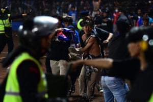 People carry a man after a football match between Arema FC and Persebaya Surabaya at Kanjuruhan stadium in Malang
