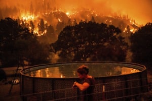 Angela Crawford leans against a fence as the McKinney fire burns a hillside above her home in Klamath National Forest