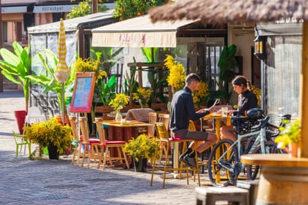 A cafe decorated with yellow flowers. Man and woman sitting with bicycle
