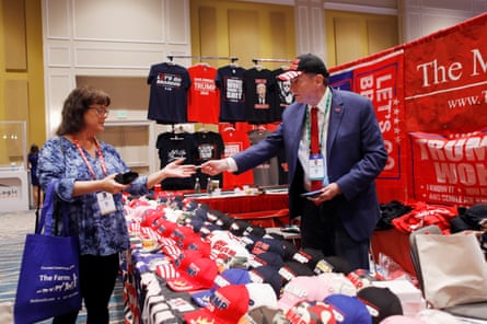 A man in a suit and cap sells Trump merchandise to a woman.