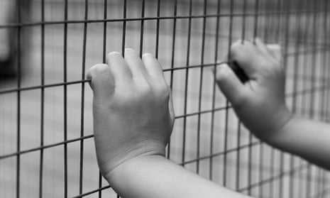 A child's hand grabbing a metal fence, shot in black and white