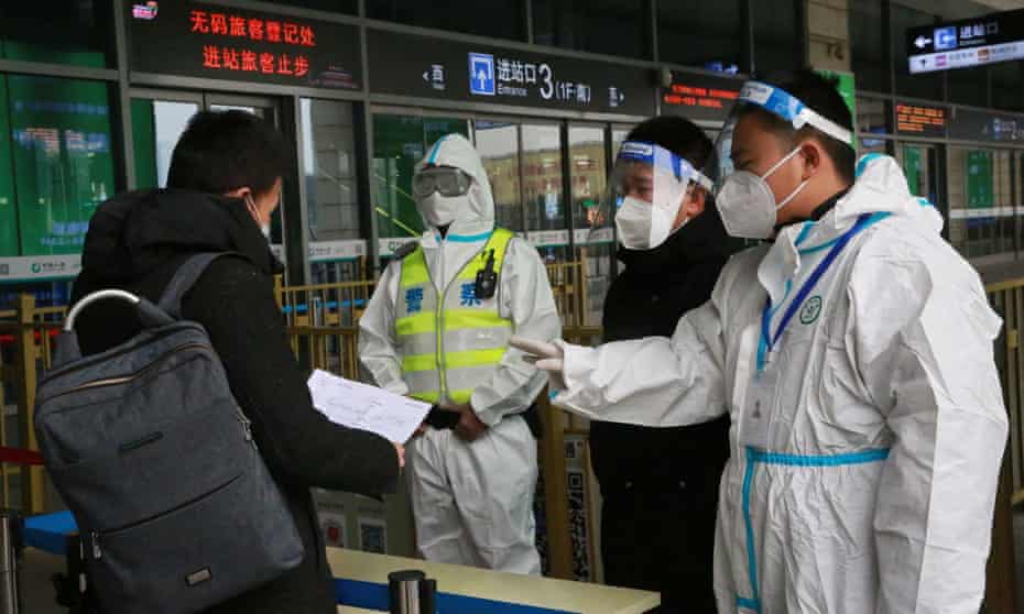 Police and staff members inspect the documents of a traveller at an entrance to a railway station in Xian.