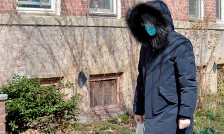 A person wearing a mask walks down a street a day after 60 people were brought to nearby hospitals to be tested for coronavirus, in Boston, Massachusetts.
