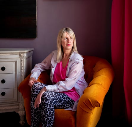 Julie Myerson sitting in a rich gold velvet armchair in a room with purple walls and deep pink curtains
