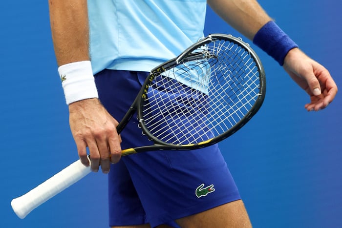 Djokovic holds his broken racket.