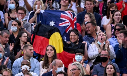 Spectators hold up the Australian and Aboriginal flags during Ash Barty’s final against Danielle Collins