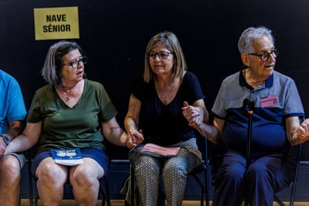 Seated older people hold hands during a class at Escuela de Espectadores Sénior