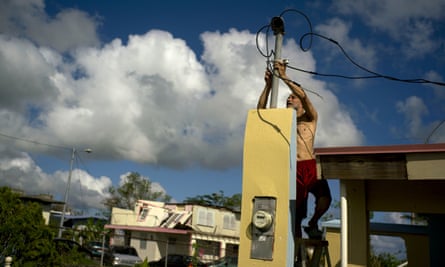 A resident tries to connect electrical lines downed by Hurricane Maria in Toa Baja, Puerto Rico, in October 2017.
