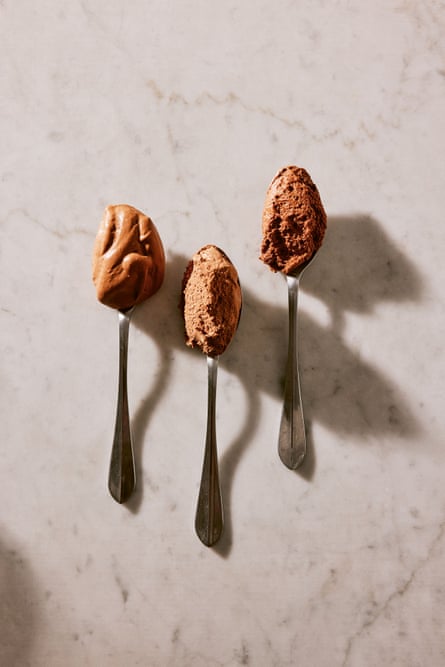 Top view of three spoons on a marble surface holding chocolate mousse.