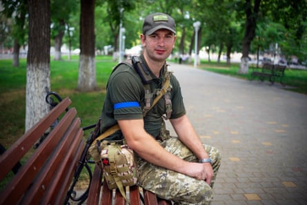 Bohdan Hotskiy, a young soldier in uniform, sits on a park bench 