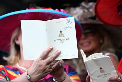 Racegoers read the day's racecard ahead of the Coventry Stakes.