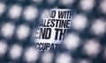 a sign urging support for Palestine is seen through a hole in an American flag