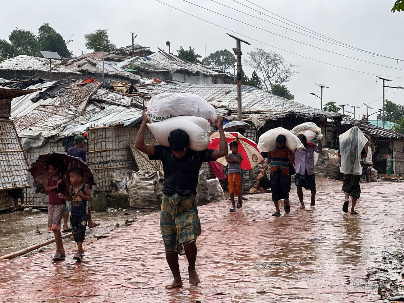 Rohingya return from aid collection points with heavy bags of supplies to their shelters