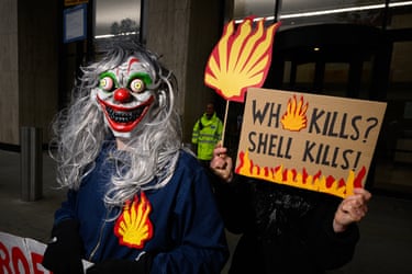 A climate protester wearing a Halloween mask holding a placard reading ‘Who kills? Shell kills’