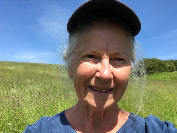 Diana Luther Powell smiles at the camera, wearing a cap, standing in a field