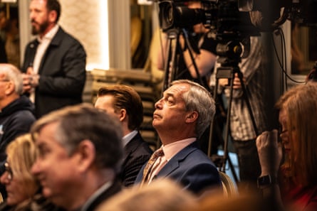 Nigel Farage watches as Zia Yusuf addresses the media.