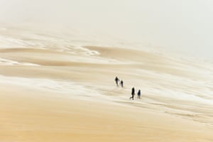 People walk on the partially snow-covered Pyla sand dune.