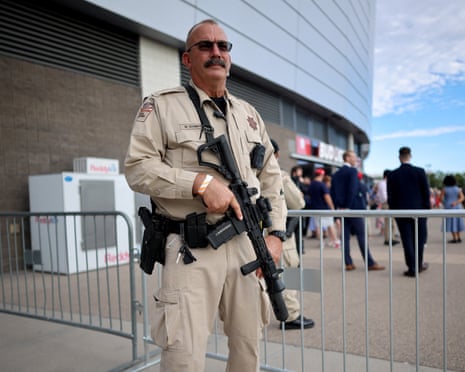 man in tan uniform holding gun stands outside