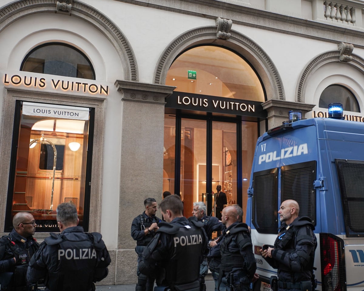 Armoured police officers gather outside a Louis Vuitton store in Milan beside a riot vehicle