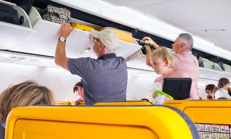 Passengers put their carry-on hand luggage into the overhead lockers on a Ryanair flight