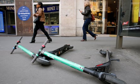 Electric scooters lying on a Paris sidewalk.
