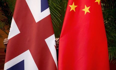 A worker adjusts British and China national flags