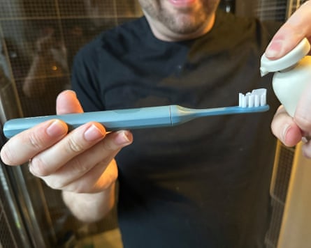 A man puts toothpaste on the Suri 2.0 toothbrush