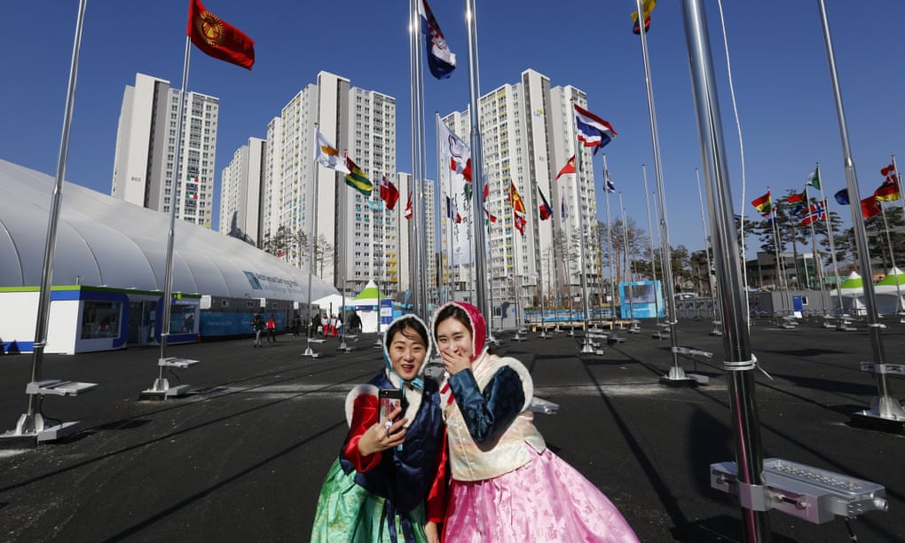 Korean girls dressed in traditional clothes take a selfie in front of the flags of competing nations at the Olympic Village in Gangneung. 