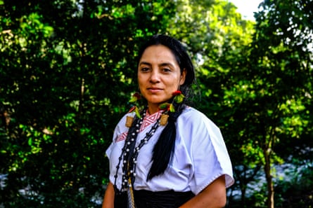 A woman stands against a leafy backdrop
