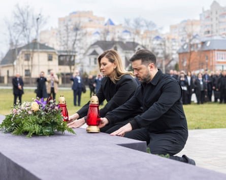Volodymyr Zelenskyy and Olena Zelenska kneel before a monument with a flower wreath laid on it