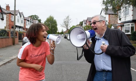 Sam Mountfield, 12, and Tony Openshaw, 66, smile as they aim megaphones at each other in the middle of a street.