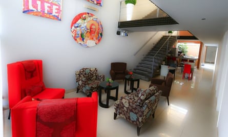 The lobby area of 3B Barranco’s B&B in Lima, Peru, with white floor tiles and a mixture of flower-patterned and bright red furniture. On the walls are pop art-style artworks.