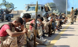 Soldiers from forces aligned with Libya’s unity government rest on the road during the assault on Sirte.