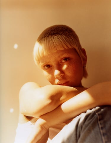 Emily in Their Room, London by Katie Burdon ‘Emily is a well-celebrated and photographed model, known for their long brown hair and feminine face. This portrait was taken in the midst of their transformation into a new, truer form of themselves. Fresh cut, freshly departed from the modelling world, sun shining. It felt celebratory!’