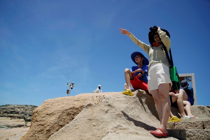 A tourist holds binoculars in front of the Taiwan Strait at the 68-nautical-mile scenic spot, one of mainland China’s closest points to the island of Taiwan.