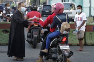 Catholic priest Adrian Magnait distributes sachets of blessed ash and prayer pamphlets outside the Saint Gabriel the Archangel Parish church in Caloocan, the Philippines