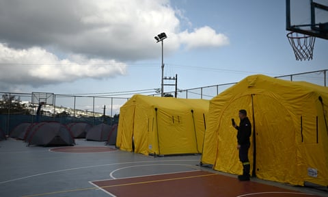 A firefighter stands amongst tents set up on a basketball court for incoming rescue personnel in Fira, on Santorini, 3 February 2025.