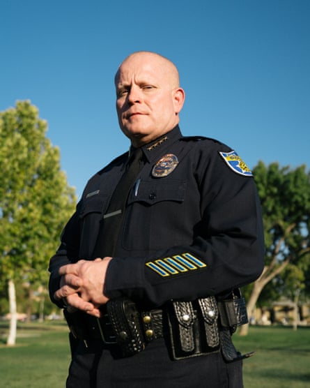 man in police uniform with park in background