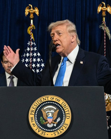 Pete Hegseth speaks during a press conference watched by Donald Trump behind him