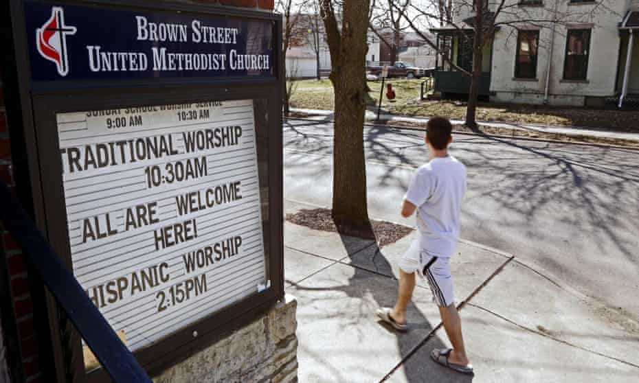 A pedestrian walks past a sign reading “All are Welcome” at Brown Street United Methodist Church in downtown in Lafayette, Indiana.