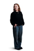 Alex, wearing baggy jeans and a black jumper and smiling.