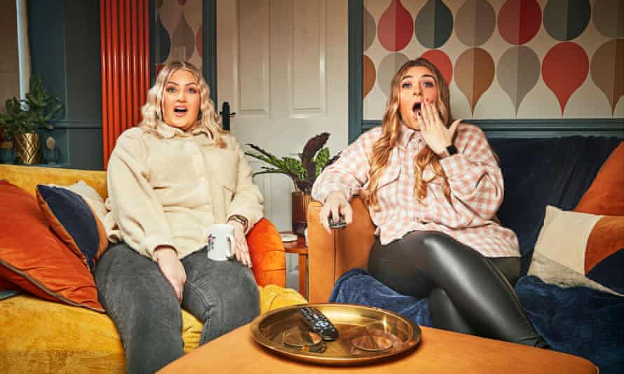 Ellie and Izzi on a yellow sofa with colorful cushions, both wearing expressions of shock or surprise