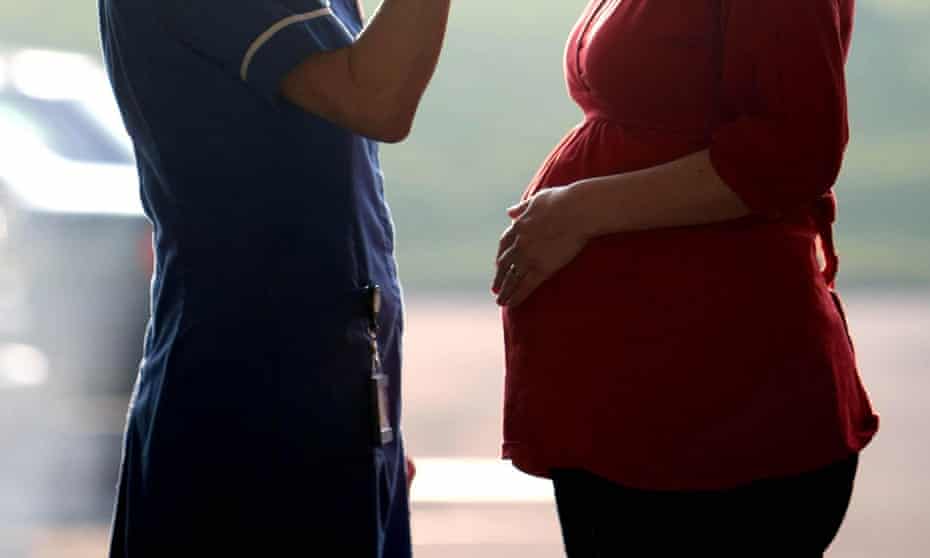 A nurse talking to a pregnant woman, seen from the shoulders down
