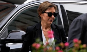 A middle-aged woman in sunglasses in front of a vehicle.