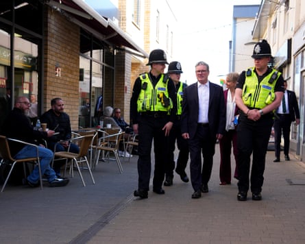 Keir Starmer and Yvette Cooper walk through a town centre with police officers.