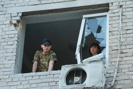 Residents look out of a broken window on Thursday morning after their apartment building was hit by a Russian missile.
