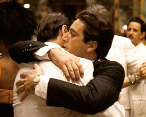 John Cazale (back to camera) and Al Pacino hug in a ballroom